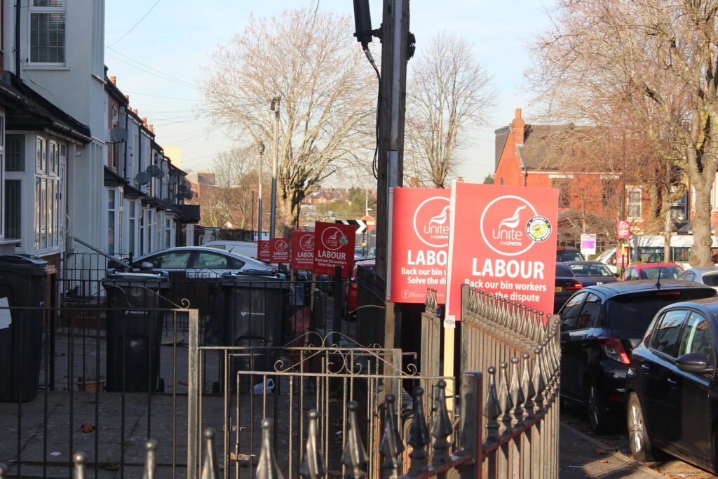 Red pickets saying "Labour: back our bin workers, solve the dispute" line the Alum Rock streets.
