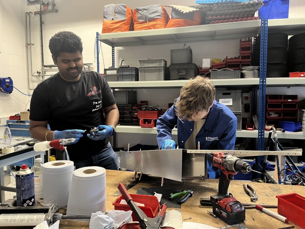 Harsha Penumadu, Technical Advisor (left) and Peter Rhodes, Deputy Chassis Lead (right), rivet the chassis together at the workshop.