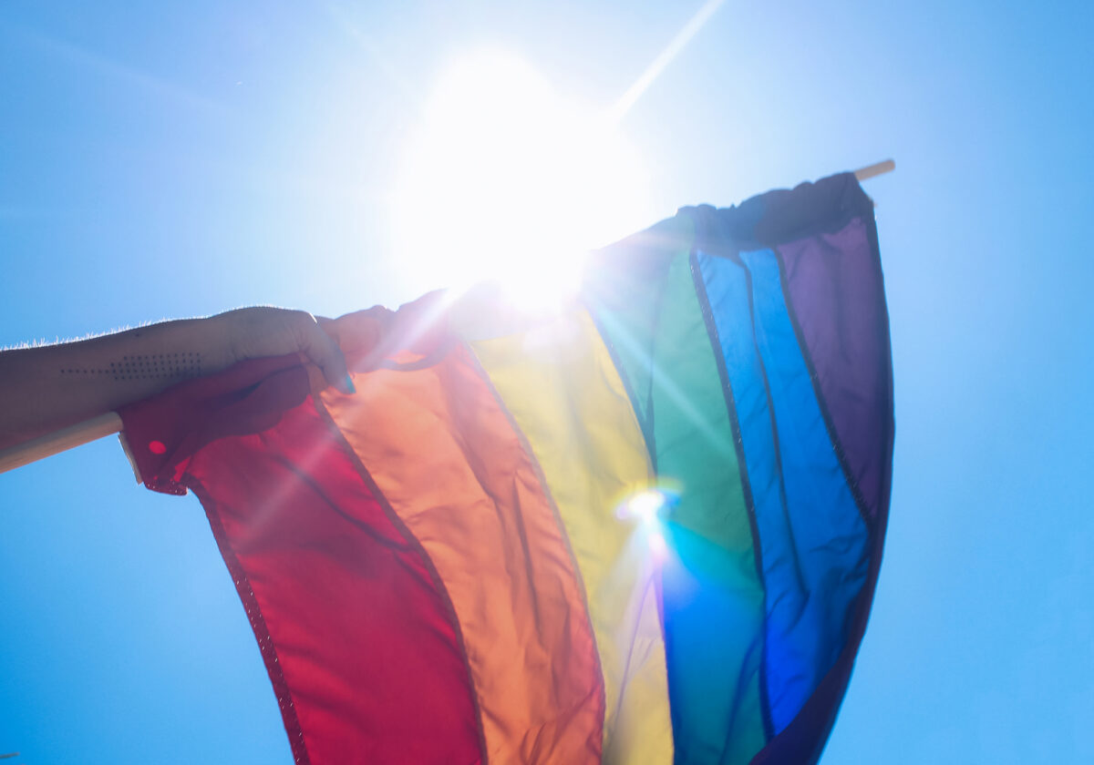 An LGBT flag being held in a person's arm.