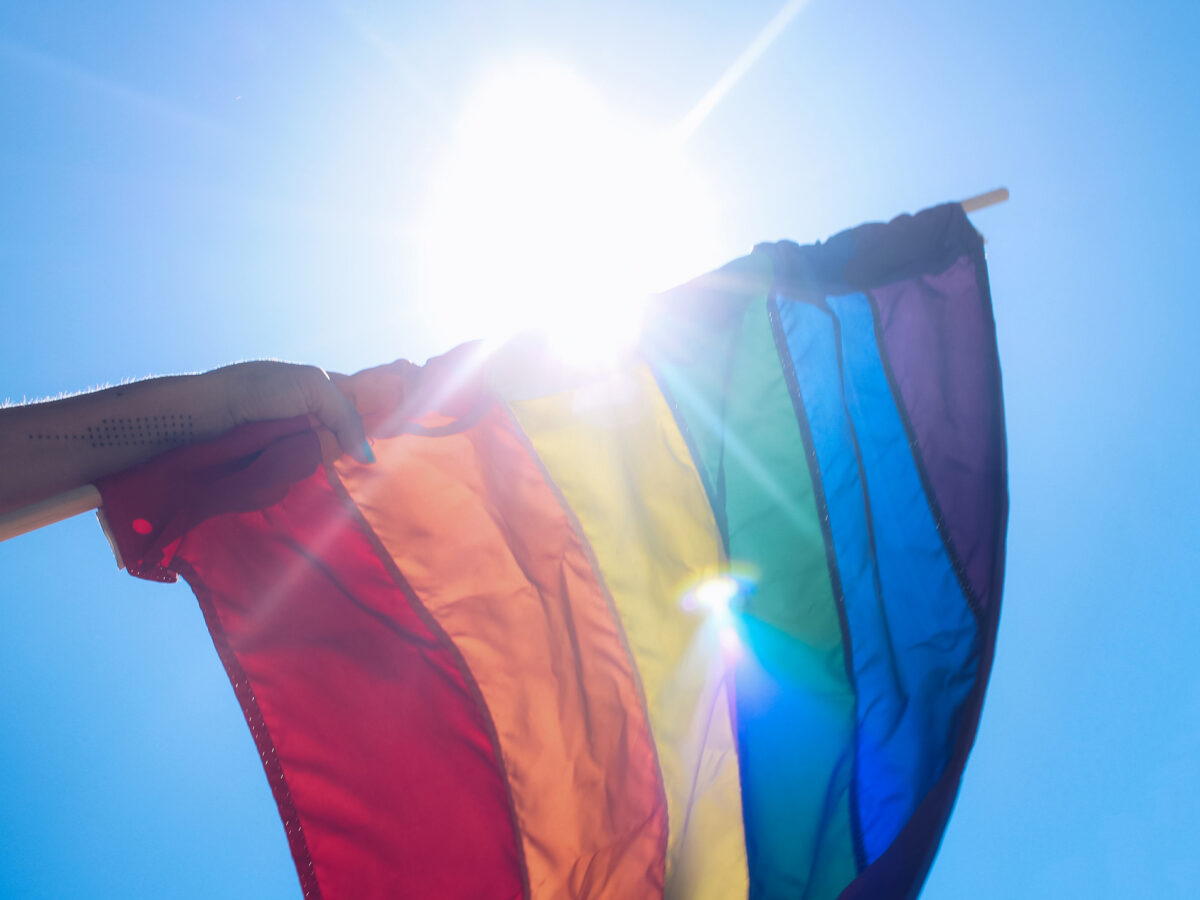 An LGBT flag being held in a person's arm.
